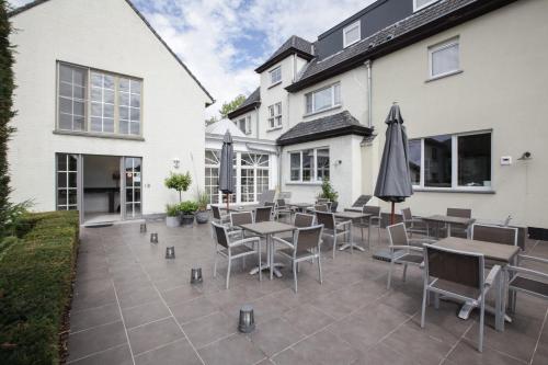 a patio with tables and chairs and an umbrella at Hotel Lepelbed in Ghent