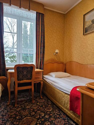 a hotel room with a bed and a chair and a window at Folwark Historic Hotel in Warsaw