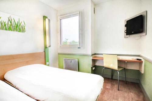 a bedroom with a bed and a desk and a television at ibis budget Besançon Ecole Valentin in Besançon