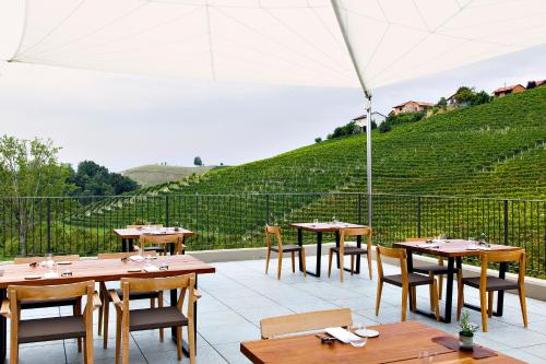 a patio with tables and chairs and an umbrella at Réva Resort in Monforte dʼAlba