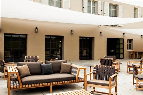 a patio with chairs and couches in front of a building at Réva Resort in Monforte dʼAlba