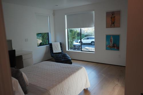 a bedroom with a bed and a chair and a window at The Hollywood House in Los Angeles