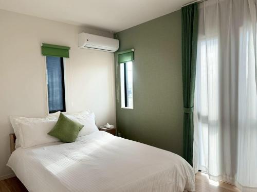 a bedroom with a white bed and a window at Akikawa Waifu 2 プレミアム木造 一棟貸切ヴィラ in Kikuchi