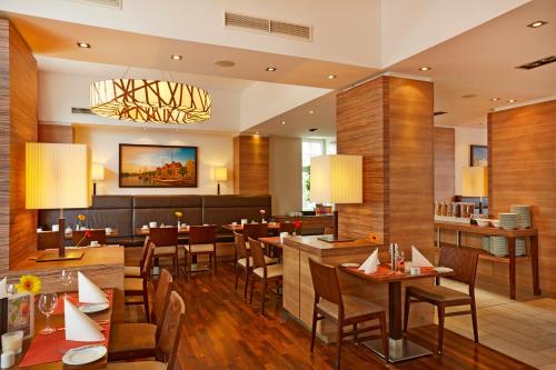 a restaurant with tables and chairs and a bar at H+ Hotel Lübeck in Lübeck