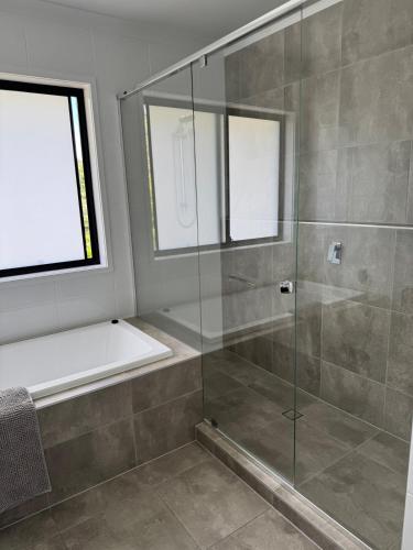 a bathroom with a glass shower with a tub at The Ponds at Mudgeeraba in Gold Coast