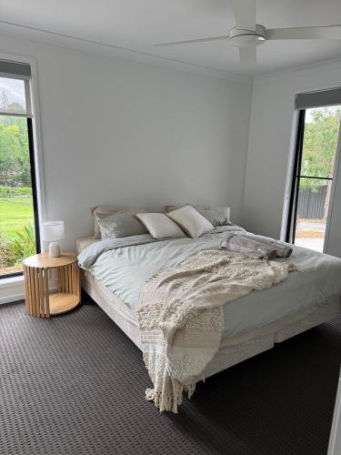 a white bedroom with a large bed and windows at The Ponds at Mudgeeraba in Gold Coast