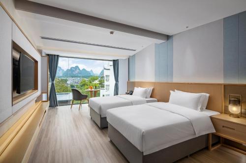 a hotel room with two beds and a television at Guilin Yangshuo Shixi Landscape Hotel in Yangshuo