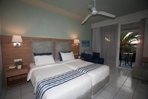 a bedroom with a large bed and a balcony at Acharavi Beach Hotel in Acharavi