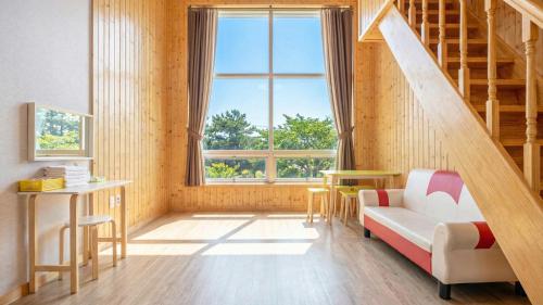 a living room with a staircase and a couch and a window at Gyeongju Gamposole Pension in Gyeongju