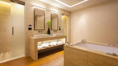 a bathroom with a tub and a sink and mirror at La Cigale Tabarka in Tabarka