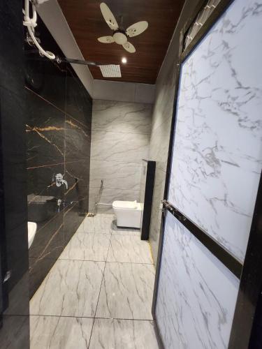 a bathroom with a toilet and a ceiling fan at Hotel Shree Sanwaliya in Ujjain