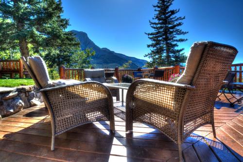 three wicker chairs and a table on a deck at Overlander Mountain Lodge in Jasper
