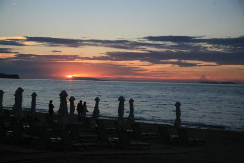 a group of people standing on the beach watching the sunset at Acharavi Beach Hotel in Acharavi