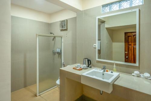 a bathroom with a sink and a shower and a mirror at Grand Melka Hotel in Lovina