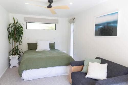 a bedroom with a bed and a couch at Hot Water Hideaway in Hotwater Beach