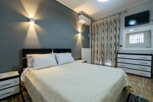 una camera da letto con un letto bianco e una TV a parete di Vila Dhimitri a Korçë