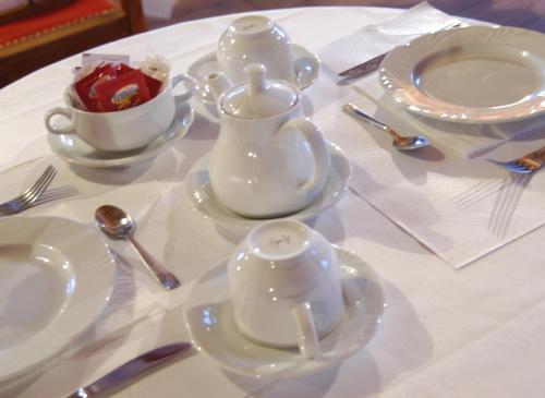 a table with white dishes and tea sets on it at Hotel La Villa della Regina in Gressoney-la-Trinité