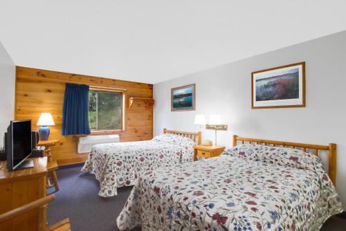 a hotel room with two beds and a television at Super 8 by Wyndham Lake George/Warrensburg Area in Warrensburg