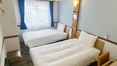 two beds in a small room with a window at Toyoko Inn Sendai Nishi-guchi Hirose-dori in Sendai