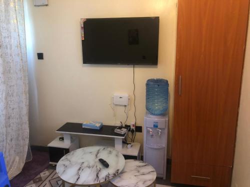 a room with a tv and a table and a stool at Hornville suites in Ongata Rongai 