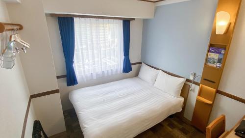a small bed in a small room with a window at Toyoko Inn Sendai Nishi-guchi Hirose-dori in Sendai