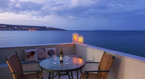 a table with two chairs and a bottle of wine at Minos Apartments & Studios in Sitia