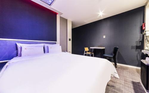 a bedroom with a large bed and a blue wall at Donkey Hotel in Bucheon