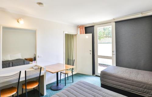 a hotel room with a bed and a table and chairs at Cottonwood Motor Inn in Mildura