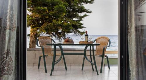 a table with two chairs and a bottle of wine at Minos Apartments & Studios in Sitia