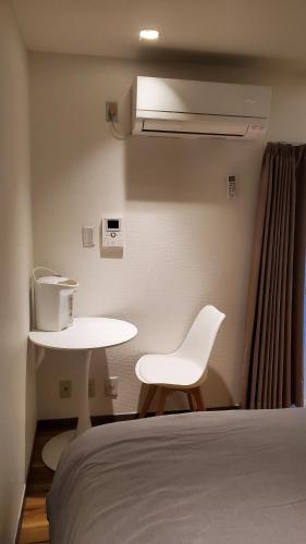 a white bed with a white chair and a table at Sunny Haven in Tokyo in Tokyo