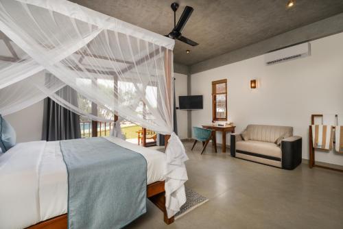 a bedroom with a bed with a white canopy at Arinna Beach Resort in Tangalle