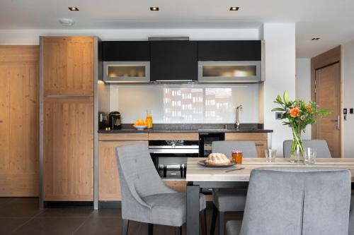 a kitchen with a table and chairs in a room at MGM Hôtels & Résidences - Résidence Manaka in Aime-La Plagne