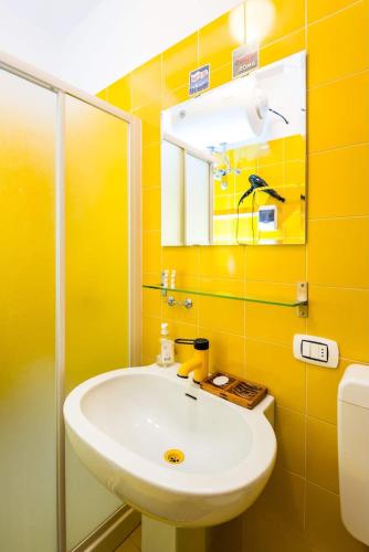 a yellow bathroom with a sink and a mirror at Terrace with a view! in Moltrasio