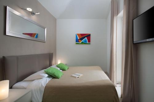 a bedroom with a bed with green pillows and a television at Istrian Villa Happy House in Nedeščina