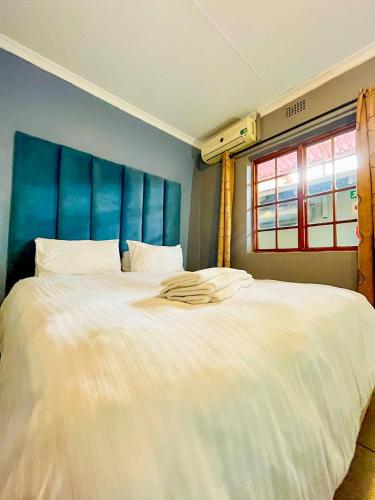 a large white bed in a room with a window at Palmetto guesthouse in Mahikeng