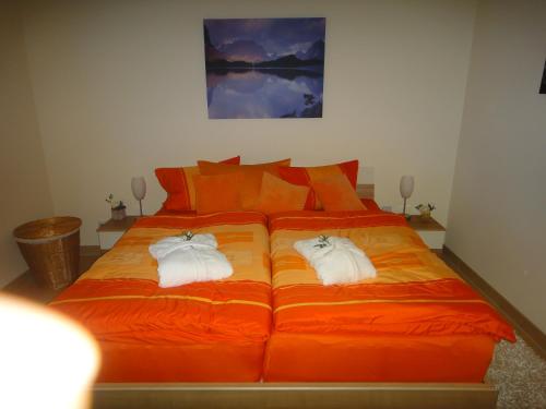 an orange bed with two white towels on it at Fewo31, exklusive Apartments, 2 Minuten vom Strand und Alten Strom in Warnemünde