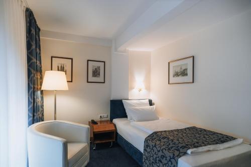 ein Hotelzimmer mit einem Bett und einem Stuhl in der Unterkunft Hotel Viktoria in Köln