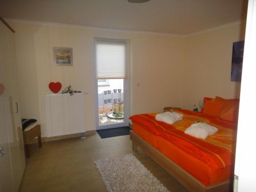 ein Schlafzimmer mit einem Bett mit orangefarbener Bettwäsche und einem Fenster in der Unterkunft Ferienwohnung Nr.31 in Warnemünde