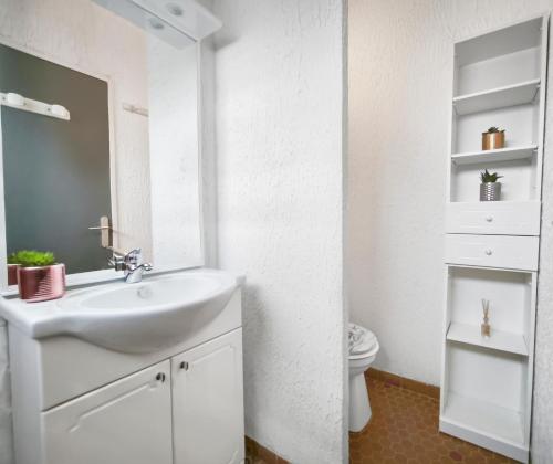 a white bathroom with a sink and a toilet at Studio Cosy avec terrasse et parking privé in Cap d'Agde