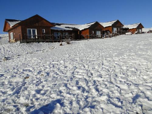 a snow covered hill with a house in the background at Cabañas Teuepen in El Calafate