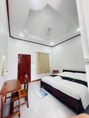 a bedroom with a bed and a table and a desk at Nongkhiaw Chansai Guesthouse in Nongkhiaw