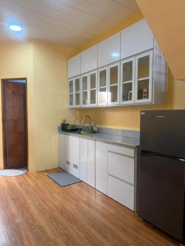 a kitchen with white cabinets and a black refrigerator at Apt101 Guest House in Bacoor