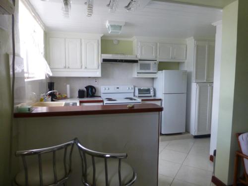 a kitchen with white cabinets and a white refrigerator at Hastings Towers 3D Studio Apt Opp Beach in Bridgetown