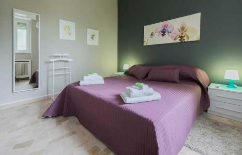 ein Schlafzimmer mit einem lila Bett mit Handtüchern darauf in der Unterkunft Milano Colletta Apartment in Mailand