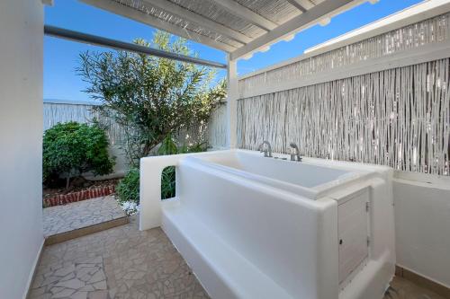 a white bath tub in a bathroom with a fence at Heliotropio Studios & Apartments in Pollonia