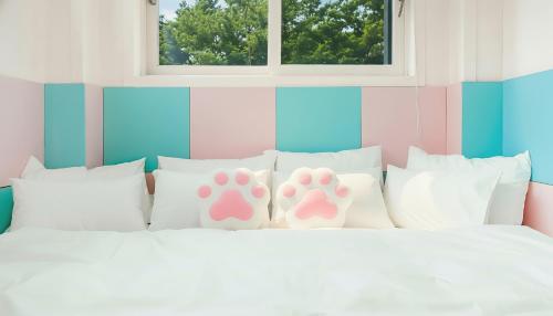 a bed with pink and white pillows with footprints on them at Pocheon luxjay pet Pension in Pocheon