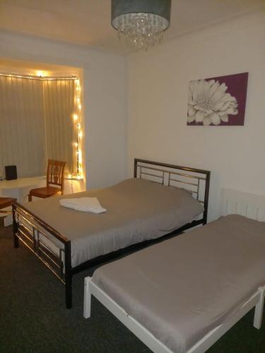 a bedroom with two beds and a chair and a chandelier at 3 Bedroom Apartment near the Beach in South Shields