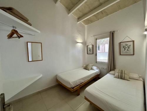 a room with two beds and a window at Apartamentos Islanders in Cala en Forcat