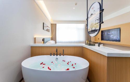 a bathroom with a white tub and a sink at Shiershan · Yuntang Hotel in Qingdao