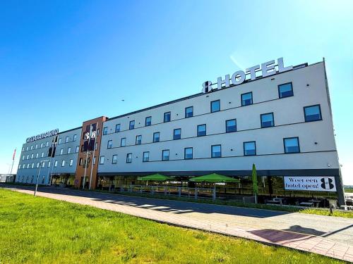 a large white building with a sign on it at Gr8 Hotel Maastricht Aachen Airport in Beek